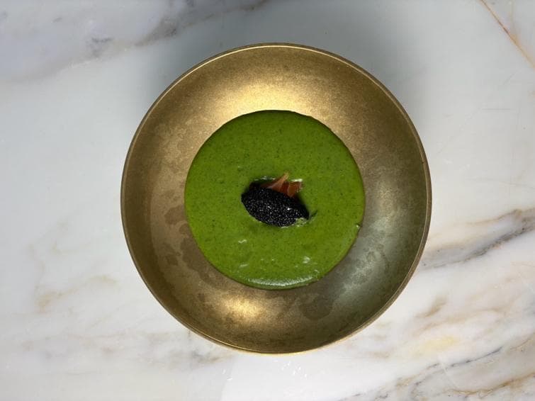 A green avocado broth around salmon and black caviar in a gold bowl