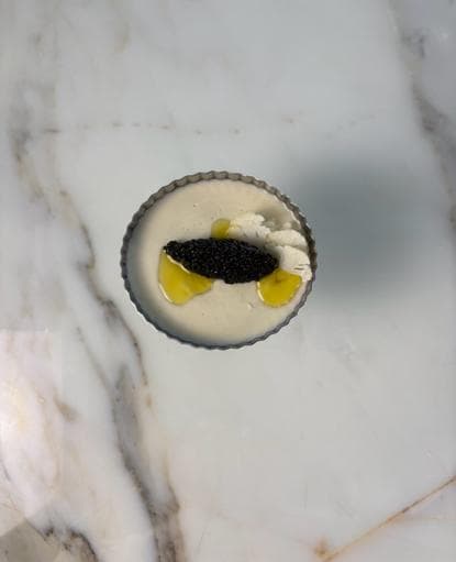 Cauliflower panna cotta in a small dish, topped with black caviar and olive oil