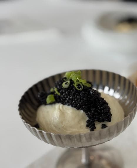 Whipped cream cheese in a fluted silver coupe, topped with black caviar and green onion