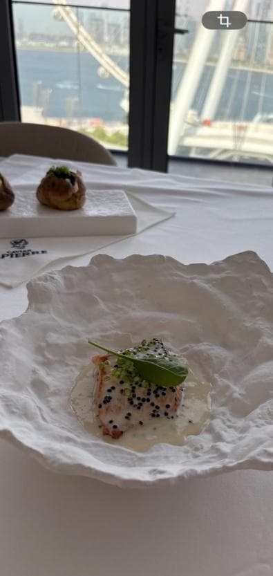 A pan-seared salmon fillet with white wine sauce and black caviar on a white plate
