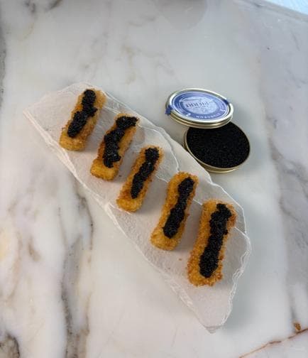 Golden panko-crusted mozzarella sticks, each topped with black caviar