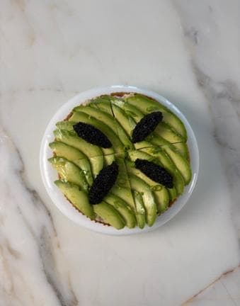 A round of crisp pastry covered with fanned avocado and quenelles of black caviar