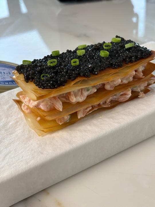 A filo mille-feuille layered with smoked salmon cream and covered with black caviar