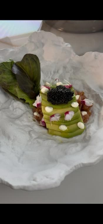 A ring of smoked salmon tartare under sliced avocado, sour cream and black caviar
